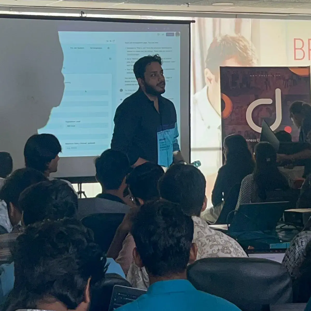 Adeen presenting to a room full of developers at laptops
