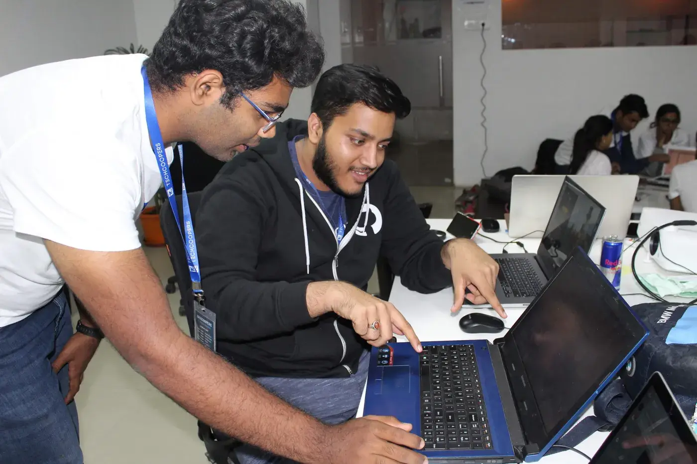 Adeen pointing at code on a laptop at a hackathon