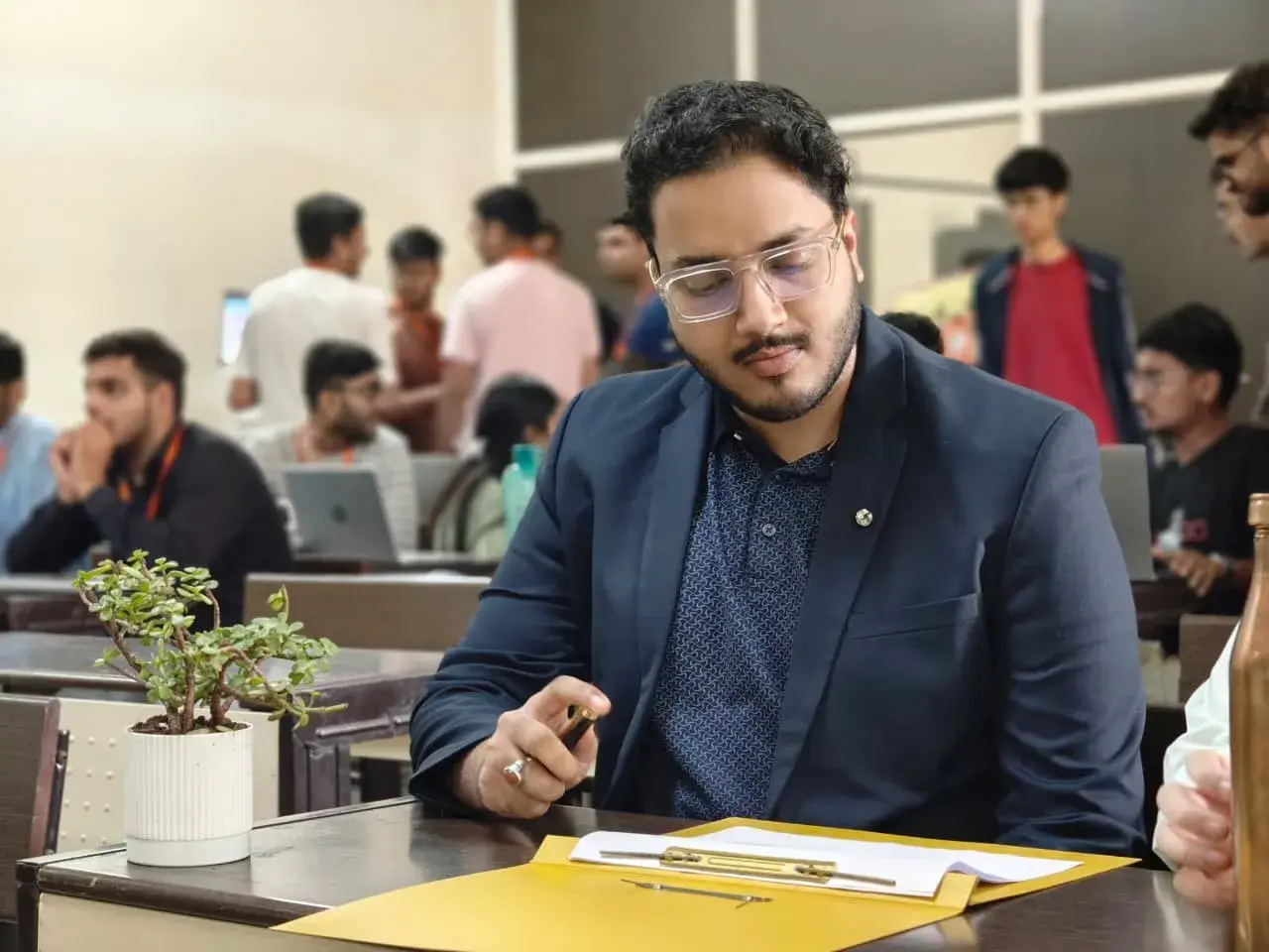 Adeen at his desk with his team working behind him